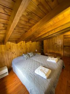 1 dormitorio con cama grande en el techo de madera en Cabaña Bigua en San Martín de los Andes