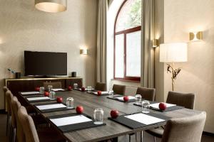 uma sala de conferências com uma mesa longa com cadeiras e uma televisão em AC Hotel by Marriott Mainz em Mainz