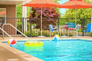 uma piscina com guarda-sóis e cadeiras e uma bola na água em Towneplace Suites by Marriott Cleveland Westlake em Westlake