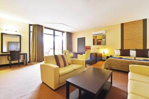 a hotel room with a couch and a bed and a table at Protea Hotel by Marriott Kampala in Kampala