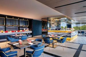 a restaurant with tables and chairs and a bar at Aloft South Jakarta in Jakarta