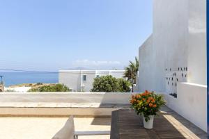 a table with a vase of flowers on a balcony at Tinos Beautiful Sunrise Apartment Near Agios Sostis Beach in Agios Sostis