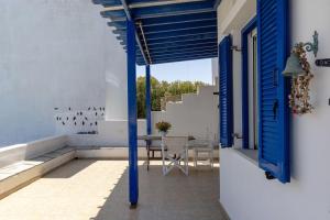 a patio with blue doors and a table with chairs at Tinos Beautiful Sunrise Apartment Near Agios Sostis Beach in Agios Sostis