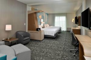 a hotel room with two beds and a couch at Courtyard Charlotte Steele Creek in Charlotte