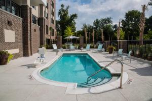 a swimming pool in a courtyard with chairs and a building at SpringHill Suites by Marriott Charleston Mount Pleasant in Charleston