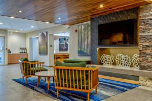 a lobby with a fireplace and chairs and a table at Fairfield Inn & Suites by Marriott Cortland in Cortland