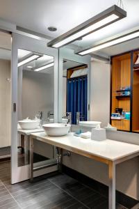 La salle de bains est pourvue de 3 lavabos et de 2 miroirs. dans l'établissement Aloft Brooklyn, à Brooklyn