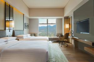 a hotel room with four beds and a flat screen tv at Chongqing Marriott Hotel in Chongqing