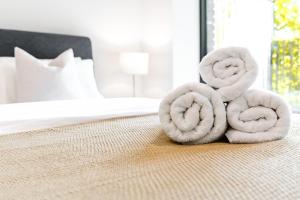 a pile of towels sitting on top of a bed at Khayat Homes - The Cosy Canex - One Bed Apt in London