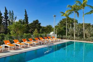a row of orange lounge chairs and a swimming pool at Aloft Miami Airport in Miami