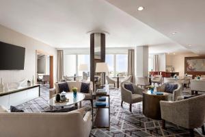 a living room with couches and chairs and a television at Sheraton Grand Warsaw in Warsaw