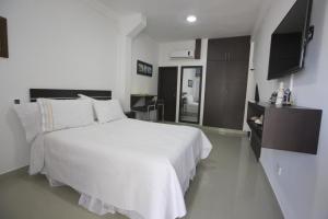 a bedroom with a white bed and a television at Hospedaje Solymar II Sarie Bay in San Andrés