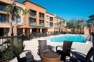 a patio with chairs and a swimming pool in front of a building at Courtyard Gulf Shores Craft Farms in Gulf Shores