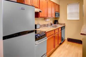 a kitchen with a white refrigerator and wooden cabinets at TownePlace Suites by Marriott Findlay in Findlay