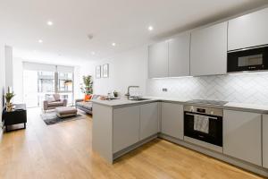 a kitchen with white cabinets and a living room at Khayat Homes - The Owelor - Two Bed in London