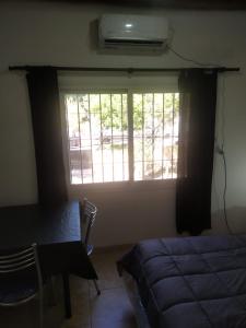 1 dormitorio con cama, ventana y escritorio en Departamentos Anchorena #5 en Luján de Cuyo