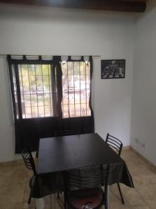 una mesa negra y sillas en una habitación con ventana en Departamentos Anchorena #5 en Luján de Cuyo
