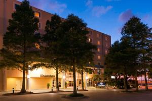 a building with trees in front of a street at Sheraton Hotel Metairie New Orleans in Metairie