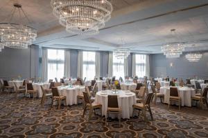 a banquet room with white tables and chairs and chandeliers at Sheraton Hotel Metairie New Orleans in Metairie