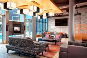 a lobby with couches chairs and a fireplace at Aloft Montreal Airport in Dorval