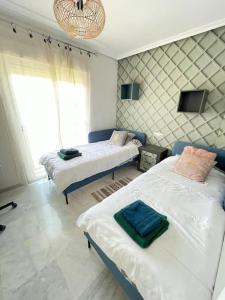 a bedroom with two beds and a chandelier at Jolie maison à Cabopino Marbella in Marbella