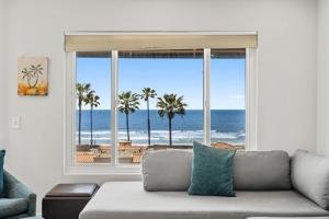 een woonkamer met een bank en uitzicht op de oceaan bij Pacific Sunsets San Miguel 16 Inviting oceanfront condo, dog-friendly, with hot tub, balcony, & W/D in Oceanside