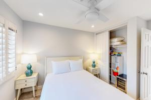 een witte slaapkamer met een bed en twee nachtkastjes bij Pacific Sunsets San Miguel 16 Inviting oceanfront condo, dog-friendly, with hot tub, balcony, & W/D in Oceanside