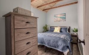 a bedroom with a dresser and a bed in a room at Driftwood - Meredith Lodging in Rockaway Beach