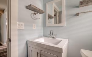 a white bathroom with a sink and a mirror at Driftwood - Meredith Lodging in Rockaway Beach +31 photos