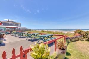 una fila de mesas de picnic frente a la playa en Beach Bliss - Meredith Lodging, en Rockaway Beach