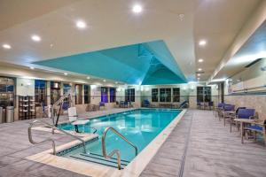 - une piscine dans le hall de l'hôtel avec des chaises et des tables dans l'établissement Residence Inn by Marriott Hamilton, à Hamilton