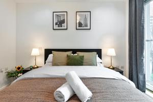 1 dormitorio con 1 cama grande y toallas. en Khayat Homes - The Cosmo - Two Bed, en Londres