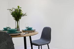 a dining table with two chairs and a table with glasses at Khayat Homes - The Cosmo - Two Bed in London