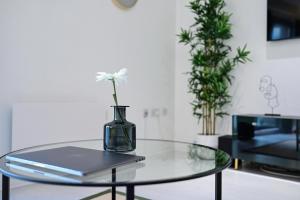 una mesa de cristal con un jarrón con una flor. en Khayat Homes - The Cosmo - Two Bed, en Londres