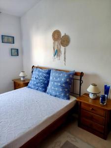 een slaapkamer met een bed met blauwe kussens en 2 tafels bij Jasmine Beachouse in Lagos