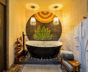 a bath tub in a bathroom with a large painting on the wall at HOLT - Villa Noria - La Casa del Barro Verde in Oaxaca City