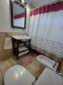 a bathroom with a sink and a toilet and a mirror at Cerro Pirámide Alojamiento in Caviahue