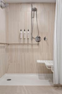 y baño con ducha y 3 botellas de champú. en Delta Hotels by Marriott Allentown Lehigh Valley, en Fogelsville