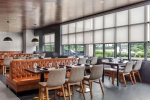 um restaurante com mesas, cadeiras e janelas em Delta Hotels by Marriott Allentown Lehigh Valley em Fogelsville