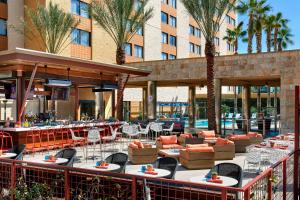 un patio del hotel con mesas, sillas y palmeras en Los Angeles Marriott Burbank Airport, en Burbank