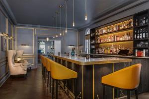 a bar with yellow bar stools in a room at Morrison House Old Town Alexandria, Autograph Collection in Alexandria