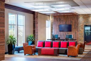 a waiting room with red chairs and a flat screen tv at Four Points by Sheraton Chicago O'Hare in Schiller Park