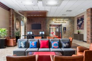 a lobby with a couch and chairs and a tv at Four Points by Sheraton Chicago O'Hare in Schiller Park