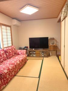 un salon avec un canapé et une télévision à écran plat dans l'établissement 柒潜の宿, à Osaka