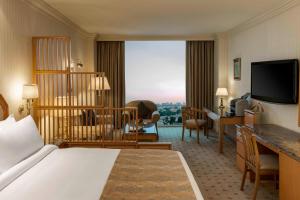 Sheraton Kuwait, a Luxury Collection Hotel, Kuwait City في الكويت: غرفة في الفندق بها سرير ومكتب وغرفة بها مكتب