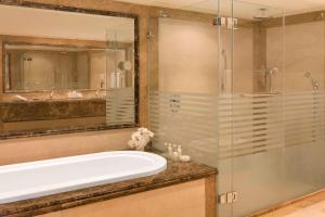 La salle de bains est pourvue d'une baignoire et d'une douche en verre. dans l'établissement Sheraton Kuwait, a Luxury Collection Hotel, Kuwait City, à Koweït