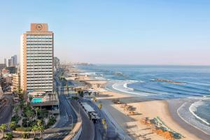 a beach with a tall building and a clock tower at Sheraton Grand Tel Aviv in Tel Aviv