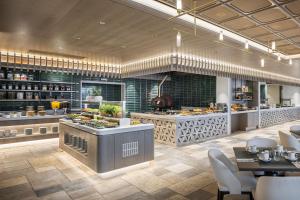 a large kitchen with tables and chairs in a restaurant at Sheraton Grand Tel Aviv in Tel Aviv