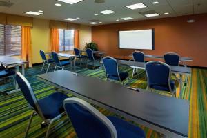 Fairfield Inn & Suites by Marriott Charleston Airport/Convention Center في تشارلستون: قاعة اجتماعات مع طاولات وكراسي وشاشة بيضاء