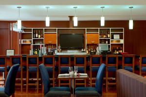 un bar con sillas azules, mesa y TV en Four Points by Sheraton Oklahoma City Quail Springs, en Oklahoma City